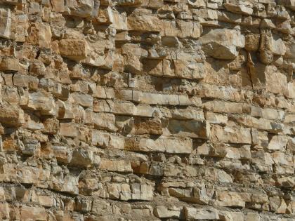 Detailaufnahme aus dem aufgelassenen Steinbruch Seitingen-Oberflacht Teilansicht einer Steinbruchwand. Das rötlich braune Gestein liegt in dünn gebankten Lagen auf, oben rechts mit teils etwas vorstehenden größeren Blöcken.