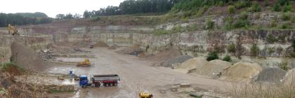 Westteil des Steinbruchs Kernen-Stetten Von erhöhtem Standort aus blickt man auf den Boden sowie drei Seitenwände eines Steinbruches. Die Wände haben mehrere Stufen und sind rechts bewachsen. Ebenfalls rechts sind am Fuß der dortigen Wand sortierte Steinhaufen zu erkennen.