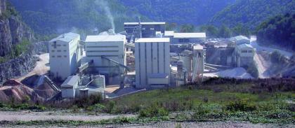 Aufbereitung in einem Kalksteinbruch auf der Schwäbischen Alb Blick auf eine rechts neben einem Steinbruch liegende Aufbereitungsanlage mit Silohäusern und Förderbändern. Im Hintergrund bewaldete Berge.