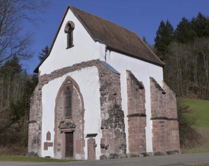 Krankenkapelle des Klosters Tennenbach nordöstlich von Emmendingen Das Foto zeigt den Gebäuderest einer Kirche oder eines Klosters. Der schmale weiße Bau wird von rötlichen Strebepfeilern gestützt. Der Eingangsbereich ist ebenfalls mit rötlichen Steinen umsäumt.