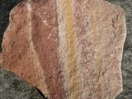 Buntsandstein-Handstück aus dem Steinbruch Rockenau Handstück eines Bruchsteines mit senkrecht verlaufenden Farbstreifen von hellrot, dunkelrot, gelb und rosa.