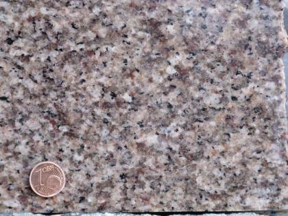 Gleichmäßiger, mittelkörniger Heidelberg-Granit Nahaufnahme eines gleichmäßigen, mittelkörnigen Gesteins. Es gibt weiße, rosa und schwarze Kristalle. Links unten befindet sich eine 1-Cent-Münze als Maßstab.