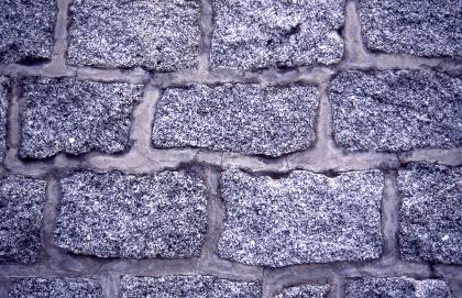 Die Fassadenverblendung eines Wasserbehälters in Ober-Laudenbach aus Granodiorit Nahaufnahme einer Mauer. Die einzelnen Blöcke sind ungefähr gleich groß und alle rechteckig, sie sind rötlichgrau und gleichkörnig.