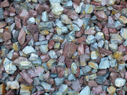 Quarzporphyre des kristallinen Grundgebirgs Nahaufnahme von ausgebreiteten kleinen Steinen. Die kantigen Stücke sind unterschiedlich gefärbt, von hellgrau bis zu rötlichem Braun.