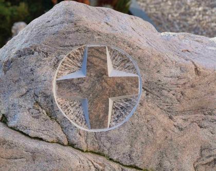 Grabmal in St. Ulrich aus einem Metatexit-Block Nahaufnahme eines graurosa Grabsteines mit stilisiertem, aus dem Stein gemeißelten Kreuz.
