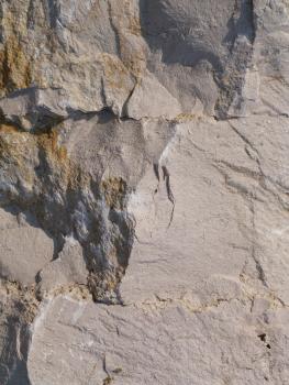Block von Hauptrogenstein im bis 2011 in Betrieb befindlichen Steinbruch Bollschweil mit parallel zur Schichtung verlaufenden Drucklösungssuturen Detailaufnahme eines großen, von einer schräg verlaufenden Bruchkante geteilten Gesteinsblockes. Rechts der Kante ist der Stein hellgrau und nur leicht zerfurcht; links sind Risse und Klüfte im Stein. Zudem finden sich hier auch rötlich braune Stellen.