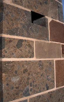 Ausschnitt vom Mauerwerk am Treppenturm des Breisacher Münsters Teilansicht eines rötlichen bis bläulich grauen Mauerwerks mit hellen Fugen und dunkleren Einschlüssen.