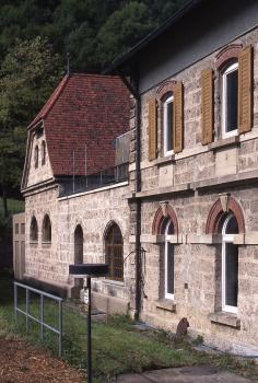 Aus Kalktuff errichtete Gebäude der Albwasserversorgung bei Seeburg Ansicht aneinandergesetzter Gebäude, perspektivisch von rechts nach links kleiner werdend. Die Gebäude bestehen aus rötlich grauem Mauerwerk.