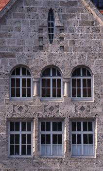 Turn- und Festhalle in Bad Urach Ansicht einer hohen Hausfassade aus rötlich grauem Mauerwerk mit zwei Fensterreihen, einem Giebelfenster und kleineren Verzierungen.