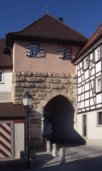 Mittelalterliches Stadttor aus Kalktuffquadern, historische Oberstadt in Mühlheim a. d. Donau Blick auf ein mittelalterliches Stadttor, ausgeführt als viereckiger Turm mit gemauerter Durchfahrt. Das Tor hat kleine Fenster mit bemalten Läden, ein rotes Dach und einen Fachwerkanbau auf der rechten Bildseite.