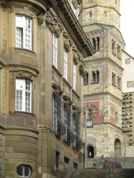 Schwäbisch Hall, Blick vom Hafenmarkt nach Osten auf das Rathaus (im Vordergrund) und die Kirche St. Michael Ansicht eines Gebäudes aus grünlichem Mauerwerk (links vorne) sowie eines Kirchturmes aus hellerem Gestein (rechts dahinter).