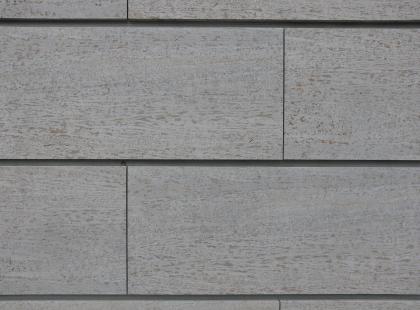 Fassadenplatten am Gebäude der pädagogischen Steinmetz- und Bildhauerwerkstatt in Grünsfeld aus Krensheimer Quaderkalk Nahaufnahme von grauen Steinplatten mit bräunlichen Schlieren und waagrechten sowie senkrechten Fugen. In der Bildmitte ist eine Geldmünze abgelegt.