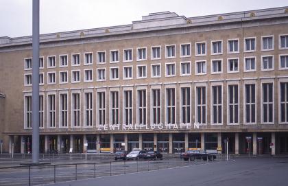 Fassade aus Steinbruch Fa. Lauster, Tengen; Flughafengebäude in Berlin-Tempelhof, Großansicht Blick auf ein größeres Gebäude mit mehreren Fensterreihen und Säulenreihe im Eingangsbereich. Das Gebäude mit dem Namen „Zentralflughafen“ hat eine Fassade aus gelblich grauen Steinplatten.