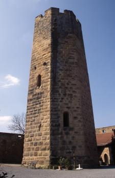 Stauferburg Steinsberg mit dem berühmten achteckigen Bergfried aus Weiler Sandstein Die Aufnahme zeigt einen hohen, achteckigen Burgturm aus gelblich grauen Mauersteinen. Der Turm ist mit Zinnen bekrönt und weist zwei dunkle Fensteröffnungen auf.