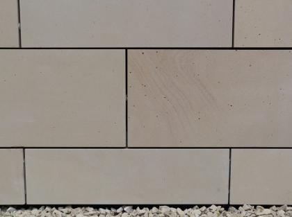 Fassadenplatten aus Niederhofener Sandstein an der Raiffeisenbank in Gundelfingen bei Freiburg Nahaufnahme glatter hellgrauer Gesteinsplatten an einer Hausfassade. Die Platten sind nicht lückenlos, sondern mit dünnen Abständen zueinander angebracht.