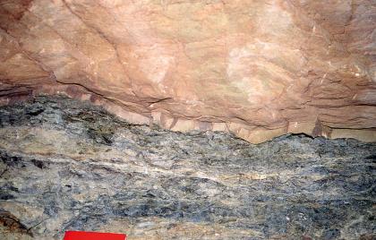 Scharfe Grenze des Schilfsandsteins (oben) gegen die unterlagernden grauen Tonsteine der Estherienschichten Teilansicht zweier scharf voneinander abgegrenzter Gesteinsschichten, oben rosa bis gelblich, unten blaugrau.
