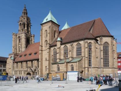 Heilbronner St. Kilianskirche von Süden Blick auf eine große Kirche aus hellbraunem Mauerwerk, mit Hauptturm und Nebentürmen, unterteiltem Hauptschiff, roten und grünen Dächern sowie wegen Bauarbeiten abgesperrtem Vorplatz.