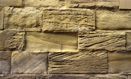 Mauerquader an der Kirche St. Georg in Bühlertann Nahaufnahme von grünlich grauen Mauersteinen, teils mit waagrecht und schräg verlaufenden Furchen.