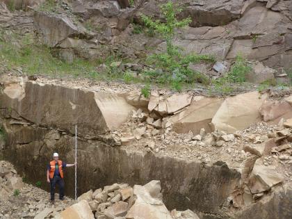 Schilfsandsteinbruch Hohenstein bei Sinsheim-Weiler, unteres Lager mit frischem Abbau Blick auf ein unteres Steinbruchlager. Das hellbraune, teils gelöste Gestein weist dunklere Bruchflächen auf. Ein Arbeiter links unten hält eine Messlatte hoch. Im Hintergrund ist ein zweites, dunkelgraues Lager.