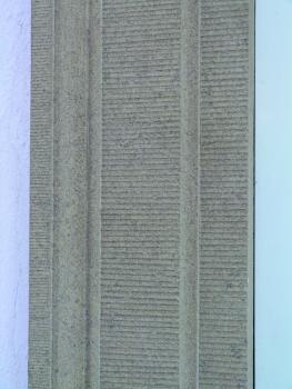 Werkstück aus Heilbronner Sandstein in der Heilbronner Innenstadt Teilansicht einer bearbeiteten Gesteinsplatte, hellbraun mit waagrechten Furchen und eingesetzt zwischen verputzten Wänden.