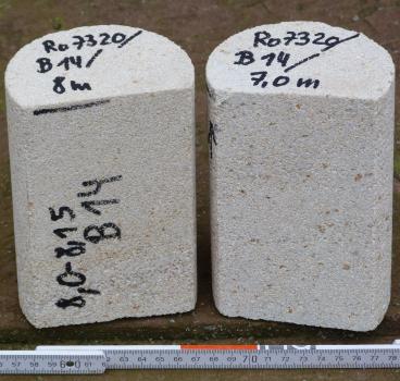 Bohrkerne im Waldgebiet Oberer Neubronn Nahaufnahme zweier kurzer runder Steinkörper, beide hellgrau mit kleinen bräunlichen Punkten. Beide Gesteine sind an der Frontseite gerade abgeschnitten sowie auf der Oberseite (links zusätzlich auf der Frontseite) beschriftet. Unten liegt eine Messlatte.