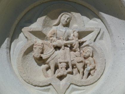 Heiliger Martin an der Martinskirche in Pliezhausen Nahaufnahme einer aus rötlich grauem Stein gearbeiteten Figurenszene mit dem Heiligen Martin.