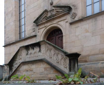 Ostportal der Stadtkirche St. Veit in Waldenbuch Blick auf ein Kirchenportal aus hellbraunem Mauerwerk, mit seitlichem Treppenaufgang und verziertem, steinernen Geländer.