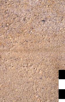 Gesteinsplatte von der Burkhardtsmühle Nahaufnahme einer leicht porösen Gesteinsoberfläche, hellbraun mit rötlich grauen Stellen im oberen Bildteil.