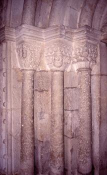 Südportal der Galluskirche in Sontheim aus Oberjura-Kalkstein Teilansicht eines Kirchenportals mit drei schmalen Säulen und verzierten Aufsätzen aus rötlich grauem Stein.