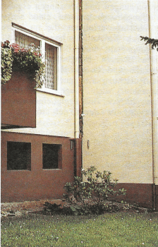 Auseinandergerissenes Doppelhaus Zu sehen ist eine Ecke eines Hauses, die von einem Riss durchzogen wird. Im Vordergrund Wiese.