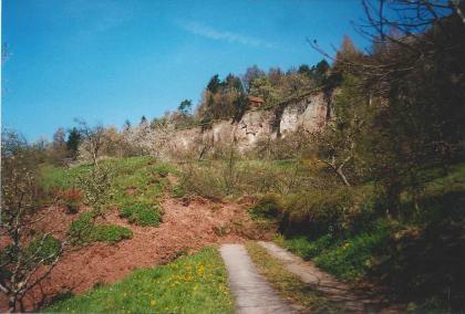 Zerstörter Weg und Rutschmasse am Kirchsteigtobel bei Urbach Ein von vorn nach hinten verlaufender Weg wird von einer rötlichen Rutschmasse von links überfahren. Links oben ist die Abrisskante der Rutschung als helle Felswand zu erkennen.