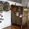 Blick in einen Museumsraum. Ausgestellt sind bebilderte Schautafeln mit dem Thema „Hohlwege“ (links), daneben steht ein kleiner Holzschuppen mit Nistkästen für Vögel.