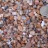 Nahaufnahme von zahlreichen Kieselsteinen in unterschiedlichen Farben und Größen. Die meisten Steine sind glatt geschliffen. Rechts oben dient eine Zwanzig-Cent-Münze als Größenvergleich.
