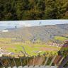 Die Aufnahme zeigt ein am Geländer des Aussichtsturmes beim Urenkopf befestigtes Landschaftsfoto im Panoramaformat.