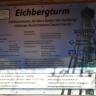 Blick auf eine halb im Schatten liegende Informationstafel des Eichbergturmes, mit Einzelheiten zu Höhe, Planung und Finanzierung des Turmes.