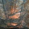 Teilansicht einer mehrfarbigen Decke in einem alten Bergwerk. Zwischen dunkelgrauen Längs- und Querstreifen liegen orange und bläuliche Flächen.