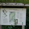 Das Foto zeigt eine bebilderte, überdachte Schautafel am Kalkofen-Erlebnispfad im Wollbachtal. Auf der Tafel ist ein Kalkbrennofen, eine Karte und eine Fledermaus zu sehen.