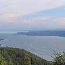 Blick aus großer Höhe über Baumwipfel und bewaldete Bergrücken auf das nordwestliche Ende des Bodensees bei Sipplingen. Links am Bildrand ist eine kleine Bucht erkennbar. Rechts bildet ein langer bewaldeter Bergrücken das jenseitige Ufer des Sees.