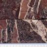 Querschnitt von zwei aufeinanderliegenden Gesteinsproben, die in Farbe und Maserung (violettgrau, rotbraun und weiß) einem Schwarzwälder Speck ähneln (Kruste, Fleisch- und Fettanteil).