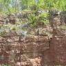 Blick auf rötlich graue Gesteinswände, links etwas hervorstehend und im oberen Teil bewachsen.