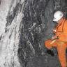 Blick auf einen Schwerspatgang in der Grube Clara. Rechts ein Bergbaumitarbeiter in oranger Schutzkleidung.