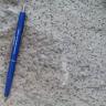 Das Bild zeigt einen rot gesprenkelten Sandstein mit einem blauen Kugelschreiber auf der linken Bildseite als Maßstab..