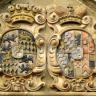 Nahaufnahme einer aus gelblich grauem Stein gefertigten Wappentafel, mit zwei unterschiedlich bemalten Wappen und flankierenden Löwenfiguren.