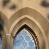 Teilansicht zweier Kirchenfenster mit umlaufenden Spitzbögen aus rötlichem Sandstein. 