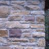 Teilansicht einer aus Steinen gefertigten Hauswand. Die Steine haben unterschiedliche Farben und Formen.
