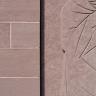 Nahaufnahme von braunrotem Gestein, links als Mauerquader, rechts als verzierter Bildstein.