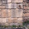 Blick auf eine Mauerecke aus unterschiedlich großen, rötlichen bis grauen Steinquadern.
