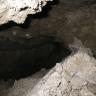 Zu sehen ist eine höhlenartige Vertiefung in einem grauen, steinigen Untergrund. Die tatsächliche Tiefe ist nicht eindeutig zu bestimmen.