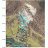 Luftbildaufnahme eines Bergrutsches oberhalb einer Siedlung, mit mehreren nachträglich eingezeichneten blauen Linien, die hangabwärts verlaufen.