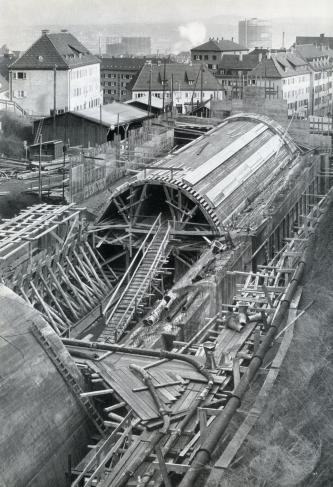 Älteres Bild in Schwarzweiß, von erhöhtem Standpunkt aufgenommen. Das Foto zeigt eine große Tunnelbaustelle in Stuttgart.